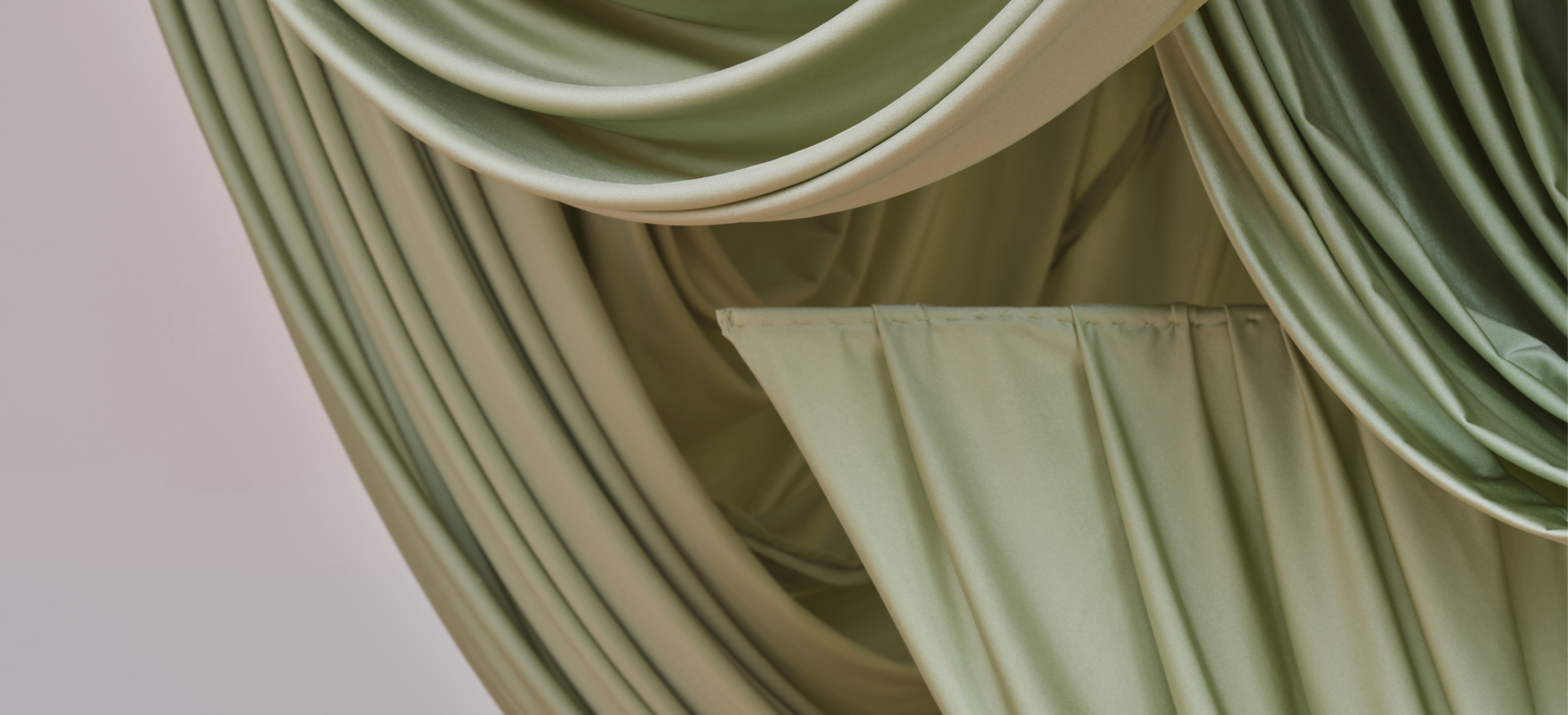 Image of folded and intertwined jade fabric on a grey background