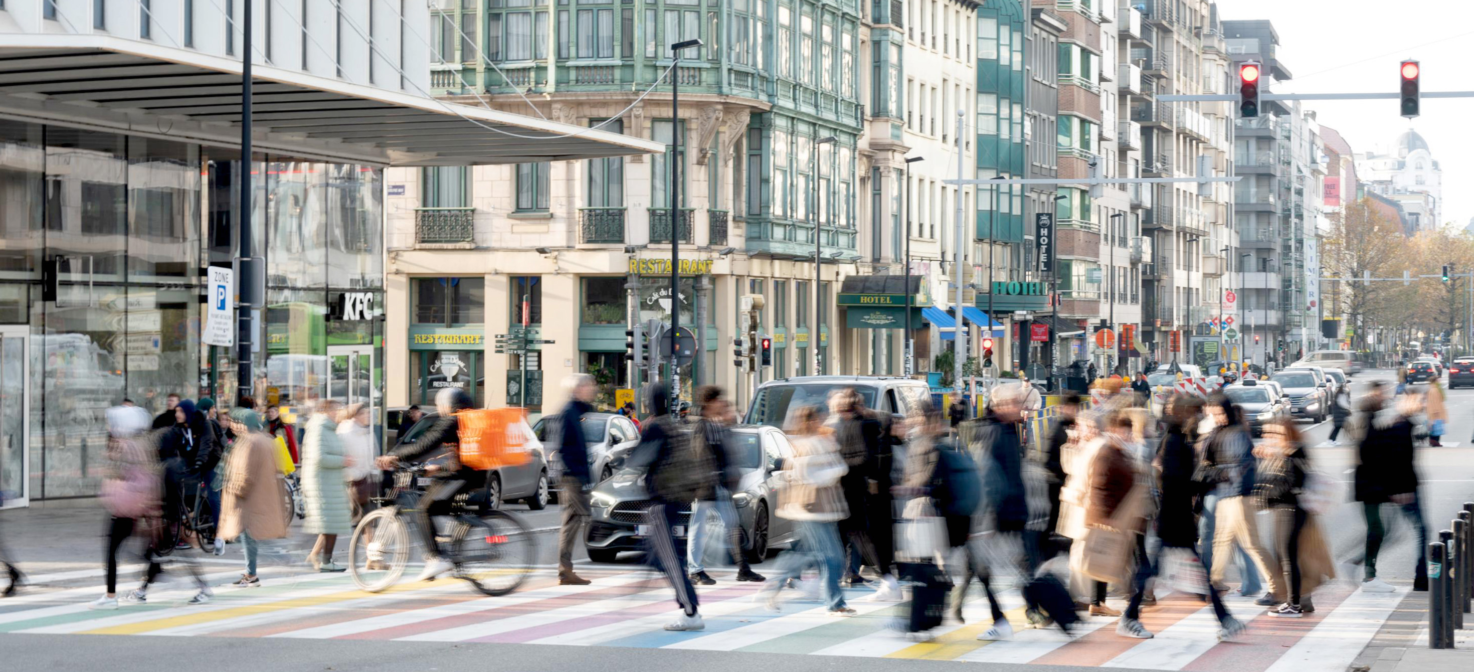 A busy city street with people walking and high rise buildings in the background. 