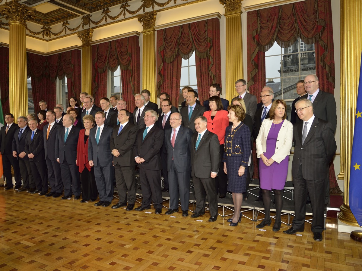 Photo of Irish and European political leaders posing for official photography in ornate room with Irish and European Union flags.