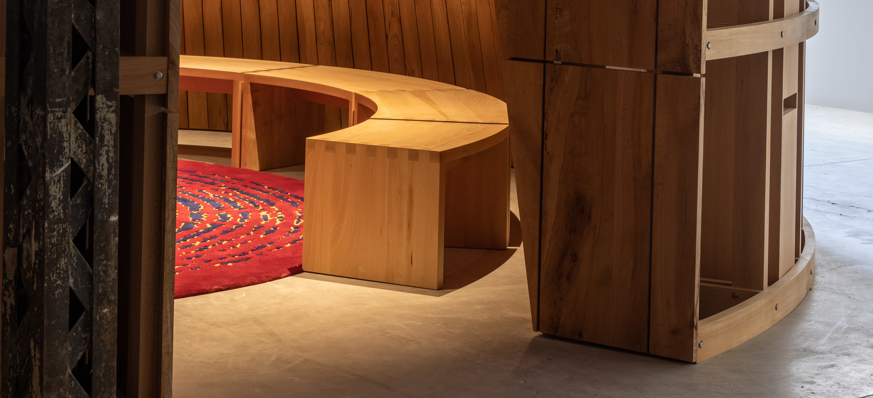 Image of the entrance to a round wooden room with red carpet and bench