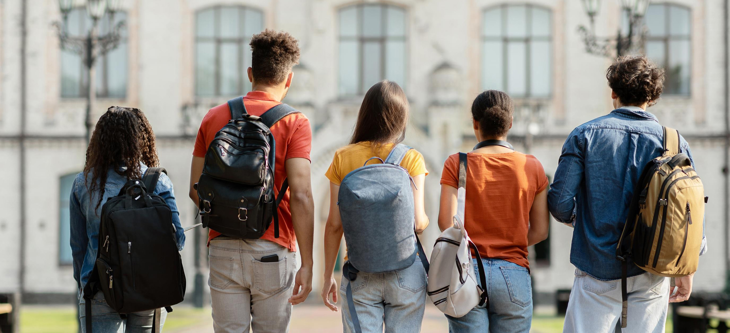 Five young people wearing backpacks standing in a row